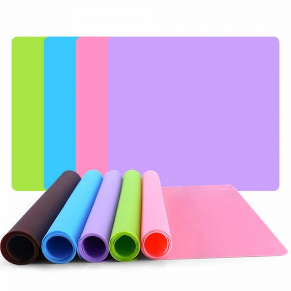 Tapis de gamelle en Silicone de couleur ' sont à plat empilés le vert, le bleu, le rose, et le violet; et cinq sont à moitié enroulés et côte à côte le noir, le bleu, le violet, le vert et le rose