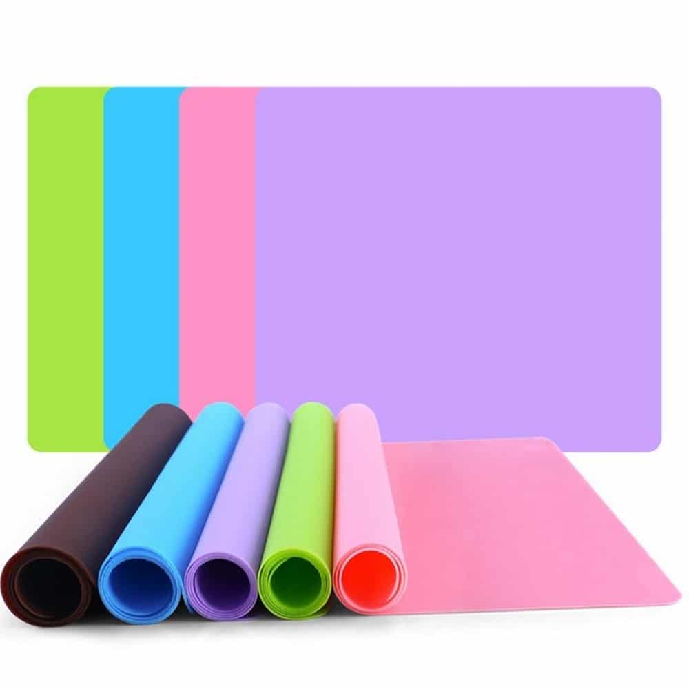 Tapis de gamelle en Silicone de couleur ' sont à plat empilés le vert, le bleu, le rose, et le violet; et cinq sont à moitié enroulés et côte à côte le noir, le bleu, le violet, le vert et le rose