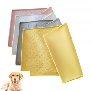 Tapis de gamelle en Silicone pour chien ' couleurs différentes empilées les unes sur les autres, jaune, gris, beige, rose et dans l'angle inférieur gauche un labrador est installé sur le ventre de face