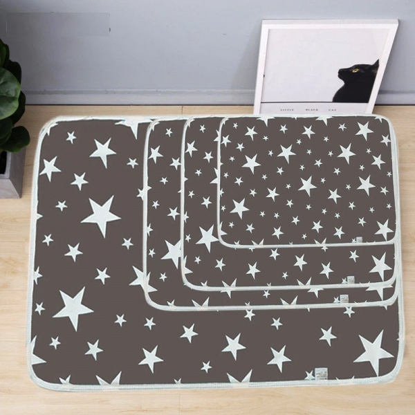 Tapis de propreté gris avec des étoiles blanches, lavable et réutilisable pour chien, avec ' taille différente, les modèles sont empilés les uns sur les autres, posés au sol, et juste à coté se trouve un petit cadre blanc avec une tête de profil de chat noir